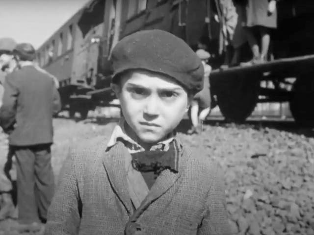 <p>The face of a young survivor. Behind him stands the train on which he has been incarcerated for the past week, along with some 2,500 of his fellow Jews</p>
